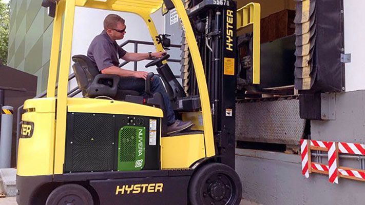 Man driving forklift, picking up cargo at a loading dock. 