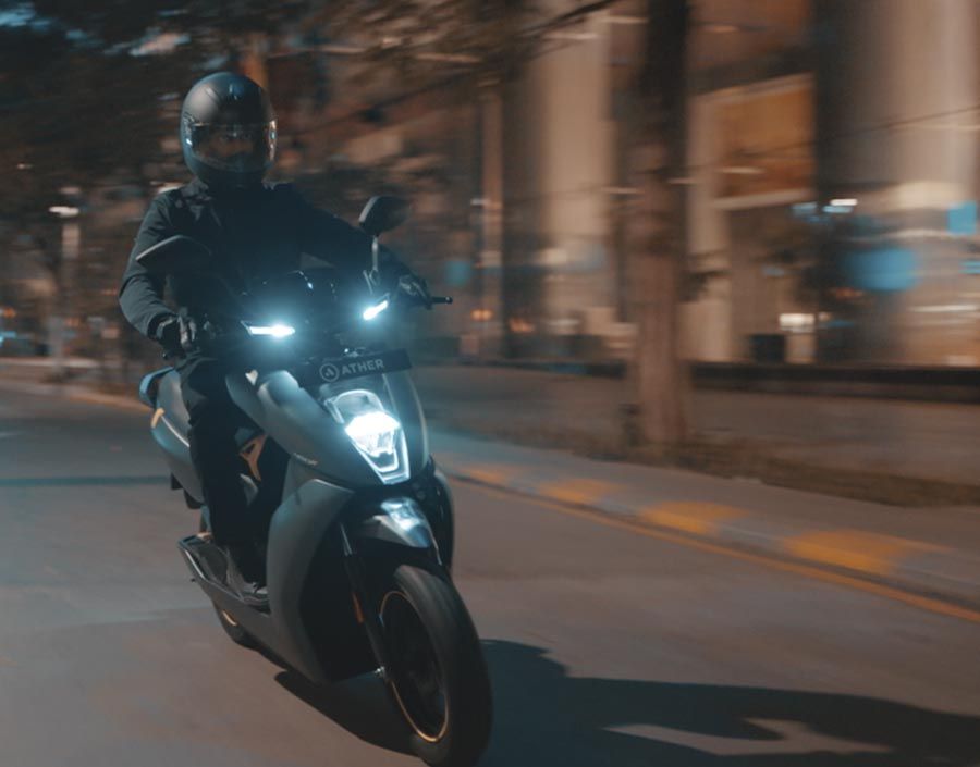 A person is driving the Ather 450x through the streets of Bangalore at night.